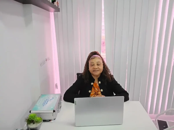 Dra. Silma Lúcia Fonseca de Souza, especialista em ozonioterapia, sentada à mesa de atendimento na clínica Sarayu, com laptop aberto e equipamentos terapêuticos ao lado, em ambiente moderno e acolhedor.